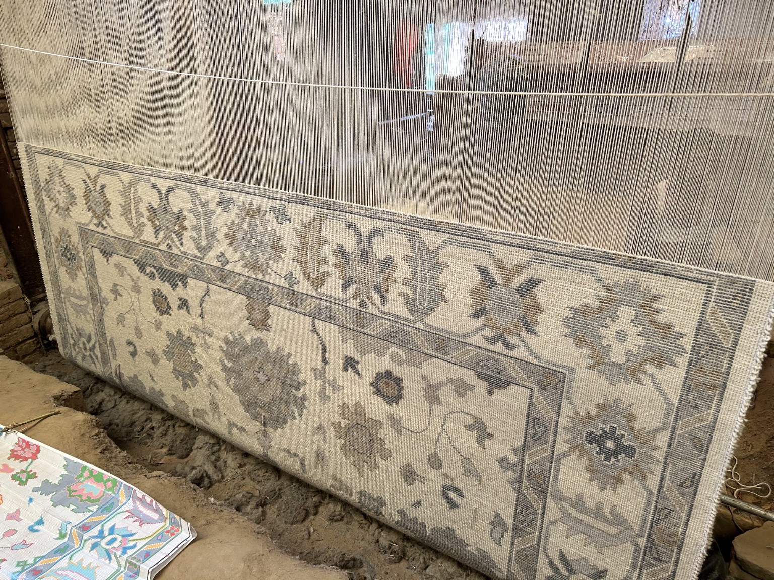 Neutral custom Oushak rug being hand-knotted on a traditional loom