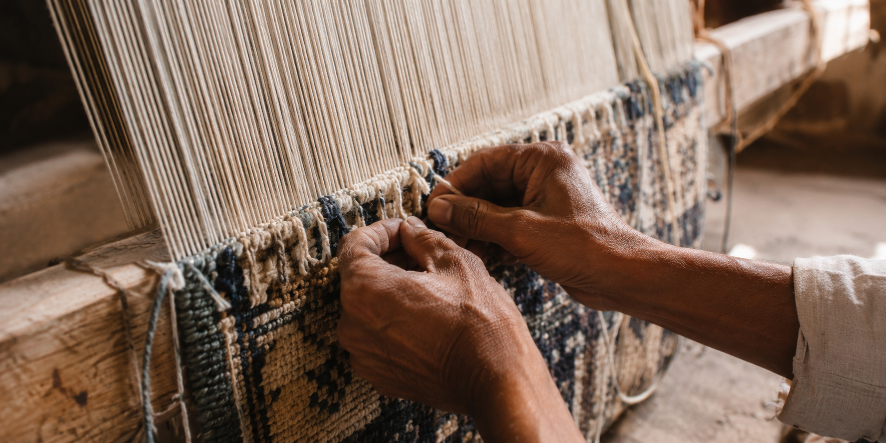 Artisan hands knotting wool on a traditional rug loom