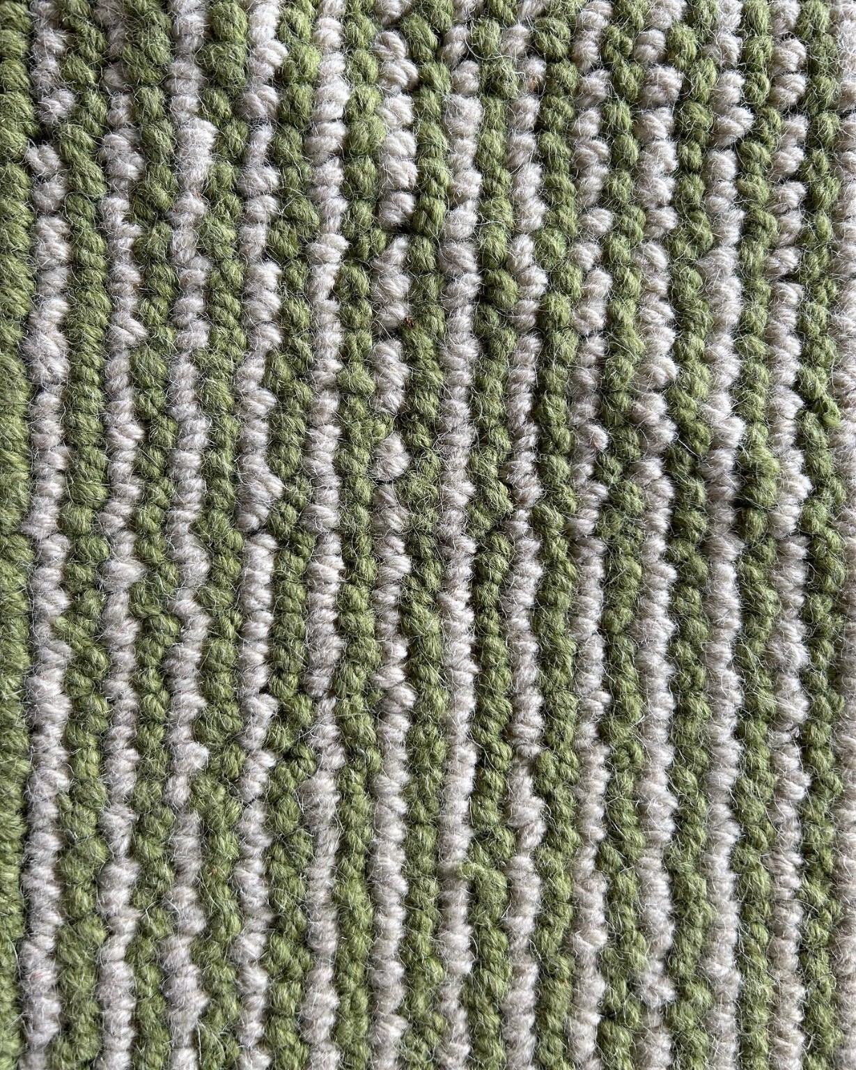 Close-up detail of green and ivory knotted wool texture