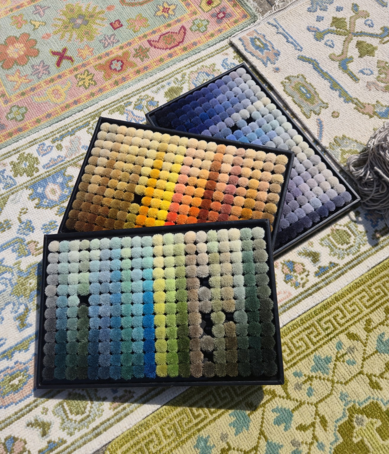 Trays of yarn colour samples arranged over patterned rugs.